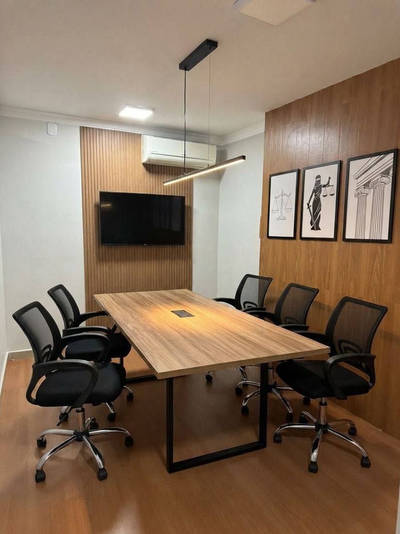 Sala de reunião com mesa de madeira e quadros com a balança da justiça